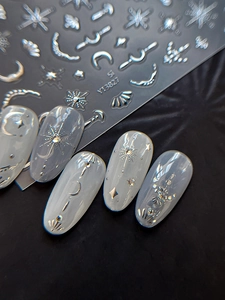 Macro detail of metallic silver star and moon embossed nail art stickers on matte base