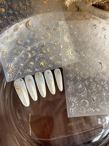 Detailed view of gold and silver sun and moon star nail art stickers on ivory nails