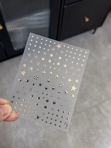 Detail shot of self-adhesive gold metallic star nail art stickers for manicure decoration