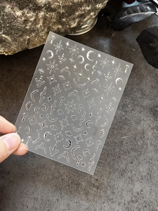 Macro shot of silver metallic moon and star nail stickers with 3D embossed texture