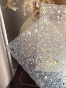 Detail of gold and silver celestial nail art stickers featuring sun, moon, and stars patterns