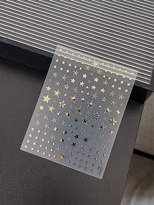 Detailed view of gold star nail art stickers with various patterns on a transparent backing