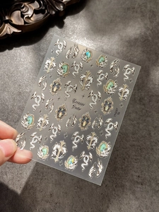 Detail von 3D-Metallic-Nagelstickern mit Vintage-Schlangen und Flügeln auf Transparent