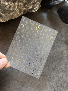 Detailed view of gold celestial nail art stickers featuring moon and star patterns
