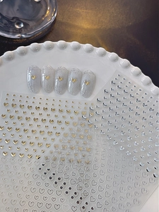 Detail of gold and silver heart nail stickers with metallic finish on ceramic plate