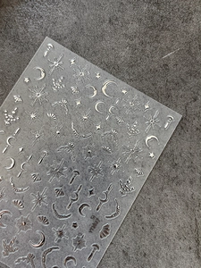Macro shot of silver metallic embossed moon and star nail stickers on stone background