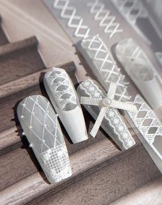 Detail of ballerina press-on nails with white lace, pearls, and ribbon bow designs