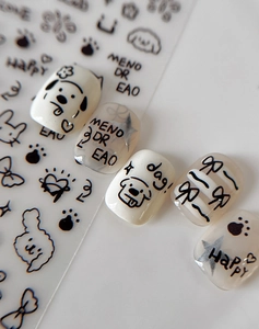 Close-up of black hand-drawn cartoon nail stickers with bow and dog designs