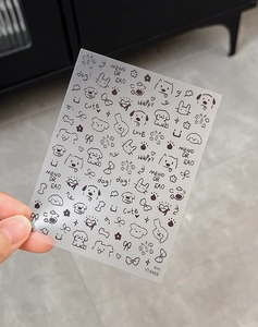 Detailed view of hand-held cartoon dog and rabbit nail art stickers with bows and flowers