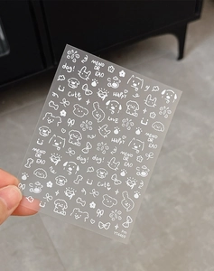 Detail view of white hand-drawn nail art stickers with cute puppies and flowers