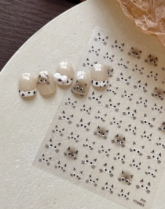 Dettaglio di adesivi per unghie con gatti e motivo mucca con punte per unghie color nude