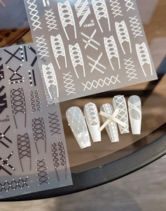 Detailed lace and cross-strap nail art stickers with pearl accents on display