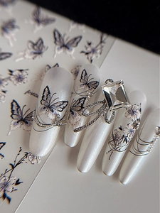 Detail of pearlescent press-on nails with 3D silver bow, square crystal, and butterfly art