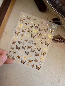 Macro shot of Golden Butterfly nail stickers with embossed gold foil details and vintage patterns