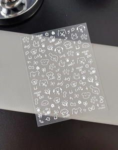 Detailed view of adhesive nail art stickers featuring white cartoon dogs and floral designs