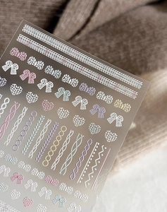 Vista macro dettagliata di adesivi per unghie 3D a rilievo con trame a maglia e fiocchi