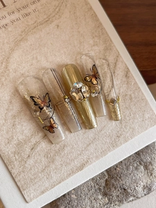 Macro detail of gold embossed butterfly nail stickers with rhinestones on long coffin nails