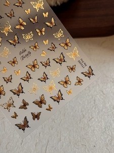 Detail macro view of golden butterfly embossed nail stickers with 3D metallic texture YT4390