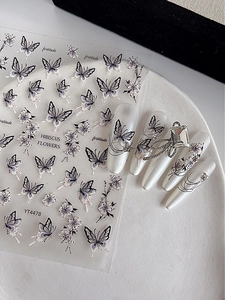 Detail of purple butterfly and flower nail stickers applied on pearlescent nails