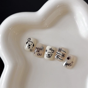Cute cartoon nail art stickers with black bows and dog designs on a white petal plate