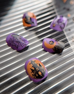 Detail of Halloween nail art stickers with purple castle, spider web and moon patterns