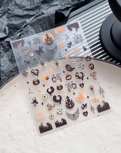 Detail of Halloween nail art stickers with black spider webs, castles and orange pumpkins