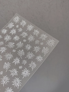 Macro shot of white embossed fireworks nail art decals with detailed linear patterns