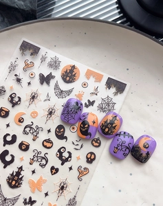 Detail of Halloween nail art stickers with orange pumpkins, ghosts, and spider patterns