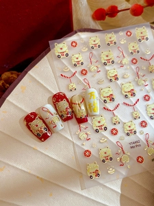 Detail of gold Maneki Neko nail stickers with lucky charms on a white folding fan background