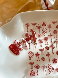 Macro detail of Chinese style red concentric knot nail stickers with gold plum blossoms