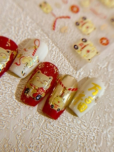 Macro view of 3D embossed New Year nail stickers with gold Maneki Neko and Yuanbao motifs