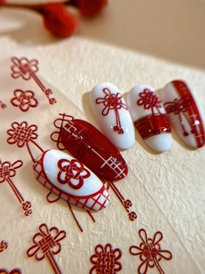 Detailed macro view of 3D embossed red concentric knot nail stickers on white base