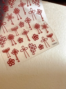 Macro detail of 3D embossed red Chinese knot nail stickers with hollow line patterns