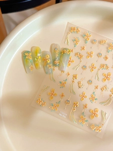 Dettaglio macro di adesivi per unghie 3D a rilievo con fiori gialli e foglie verdi