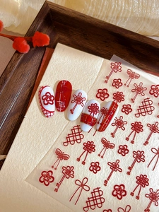 Macro shot of 3D Chinese knot nail art stickers with red floral relief patterns