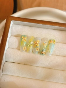 Dettaglio macro di nail art floreale 3D con sfumatura verde e dettagli in foglia oro