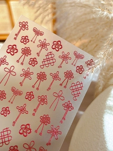 Detail of red embossed nail stickers featuring Chinese knot and floral motifs