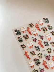 Macro detail of 3D embossed lucky cat nail art stickers with gold and red Chinese motifs
