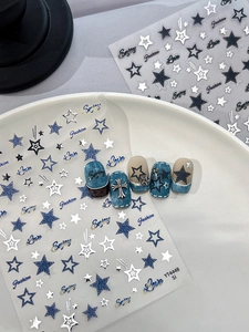 Détails d'autocollants pour ongles avec étoiles argentées et croix sur bleu denim