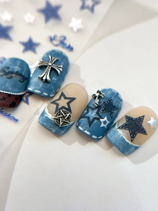 Vue macro des autocollants d'ongles texture denim avec pendentifs étoile et croix argent