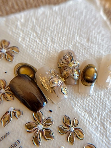 Detailed view of floral relief nail stickers with gold foil and cat eye effects