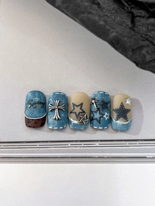 Détails de faux ongles texture denim avec breloques cœurs argentés et étoiles