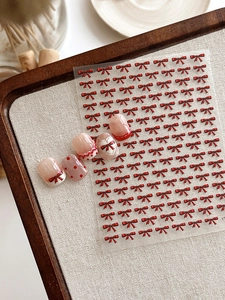 Detailed macro view of 3D embossed red bow nail art stickers and finished nail display