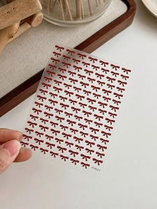 Macro detail of red bow nail stickers on adhesive sheet for DIY manicure art
