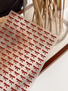 Close-up of 3D embossed red bow nail stickers with fine black outlines for nail art