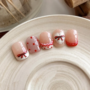 Short square pink press-on nails with red bows, polka dots and heart lace designs