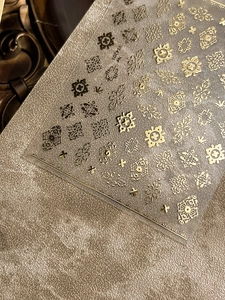 Close-up of gold and black baroque embossed nail stickers with intricate floral patterns