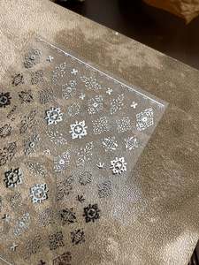 Close-up of silver baroque nail stickers with vintage patterns and adhesive backing