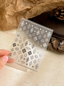 Close-up of bohemian nail art stickers with vintage silver patterns and embossed textures