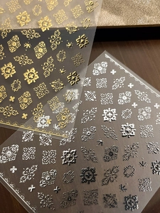 Macro detail of 3D embossed gold and silver bohemian nail stickers with baroque patterns